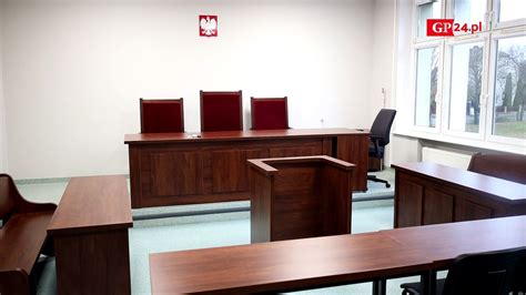 Ilustracja przedstawiająca sądową salę rozpraw z elementami symbolizującymi dług i bank